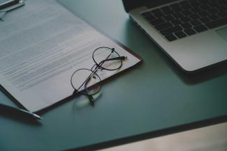 Glasses on a notebook, next to a laptop.